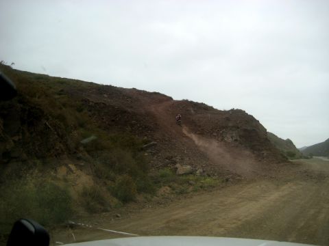 1996 Ford Bronco - A dirt bike rider navigates a challenging, dusty descent on a rocky hillside.