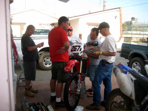 1996 Ford Bronco - Four men gather around a red dirt motorcycle with the number 267x displayed on its front.