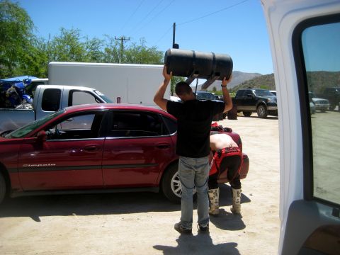 1996 Ford Bronco - People are loading a large black tank, with several vehicles in the background.