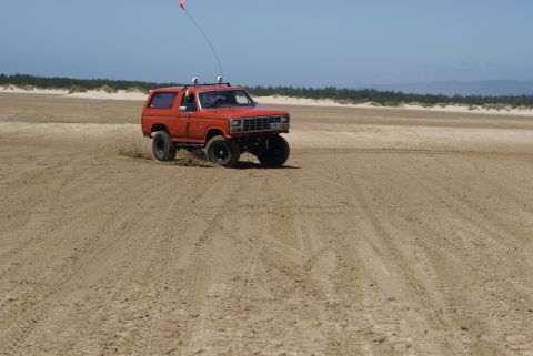 1983 Ford Bronco - This orange 1983 Ford Bronco kicks up sand as it drives along the beach.