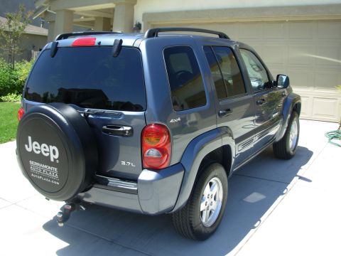 2002 Jeep Liberty - A gray 2002 Jeep Liberty is parked in a driveway, showing its rear exterior and spare tire.
