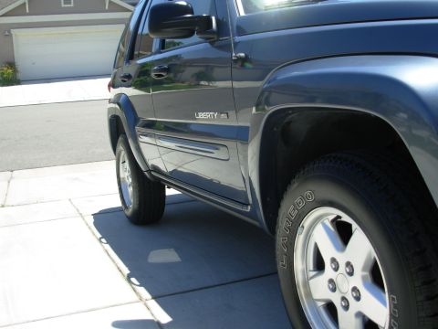2002 Jeep Liberty - The side profile of a Jeep Liberty SUV is captured in this image, showing its wheels and doors.