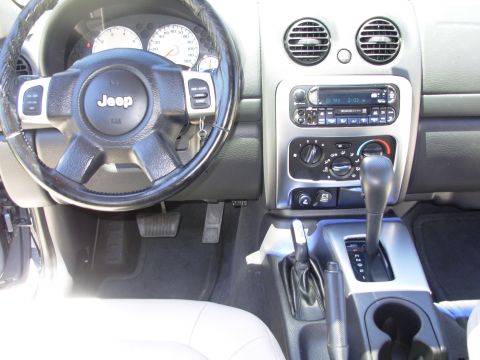 2002 Jeep Liberty - The interior of a 2002 Jeep Liberty features a prominent Jeep logo on the steering wheel and a silver-accented center console.
