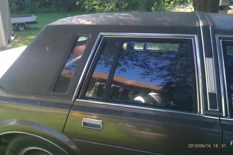 2000 Mercury Grand Marquis - The side profile of a dark-colored sedan shows its rear window and vinyl roof with chrome accents.