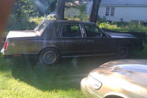 2000 Mercury Grand Marquis - This Lincoln Town Car, likely from the 1990s, is parked in a grassy yard next to another vehicle.