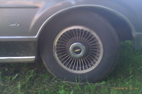 2000 Mercury Grand Marquis - Car's front wheel and fender detail with chrome trim and wire-spoke hubcap.