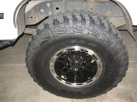 1995 Ford Bronco - A close-up of an off-road wheel and tire assembly featuring a black ION Alloy wheel with machined polished lip and a Goodyear Wrangler mud-…