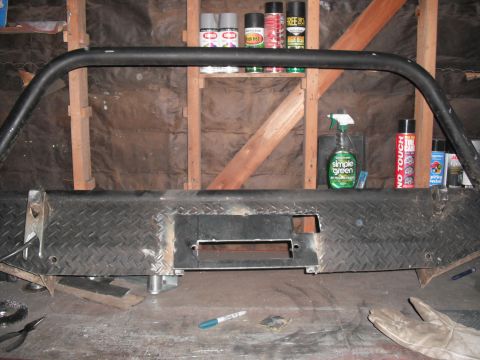 1991 Ford Bronco - A heavy-duty custom bumper with a winch cutout and brush guard is shown on a workbench, with various spray cans and cleaning supplies in th…