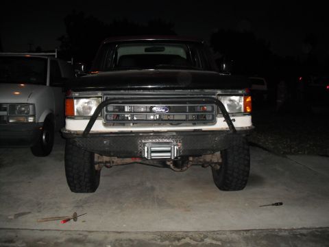 1991 Ford Bronco - Front view of a 1991 Ford Bronco equipped with a winch and brush guard. A second vehicle is visible to the left.