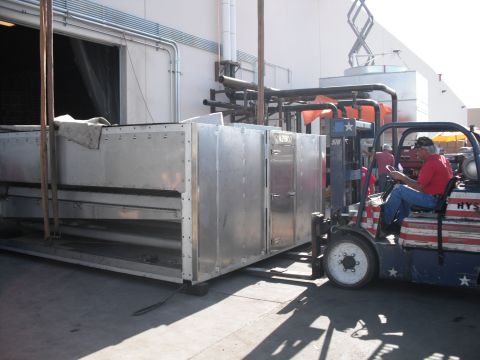 1991 Ford Bronco - A forklift transports a large metal HVAC unit outside a building.