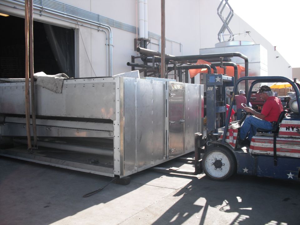 Forklift with American flag livery carrying a large, silver HVAC unit