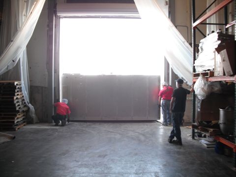 1991 Ford Bronco - Workers are closing a large loading dock door at a warehouse.