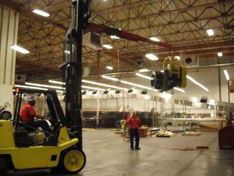 1991 Ford Bronco - Forklift operates in a warehouse, moving heavy machinery under fluorescent lights.