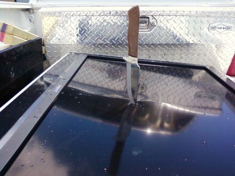 2006 Ford E350 - A knife is stuck in a flat black surface that has a Sony logo on it.