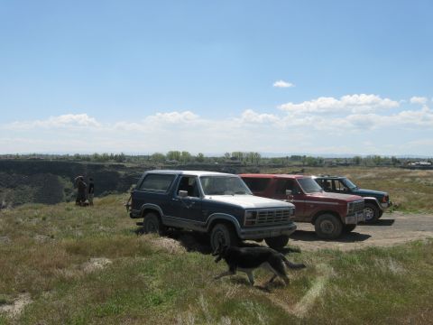 1981 Ford Bronco - A group of SUVs are parked on a grassy hill under a partly cloudy sky.