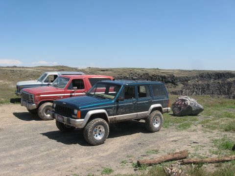 1981 Ford Bronco - A group of off-road vehicles, including a Jeep Cherokee XJ and two Ford Broncos, are parked near a canyon overlook.