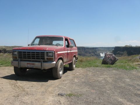 1981 Ford Bronco - This red SUV is parked at a scenic overlook with a waterfall in the background.