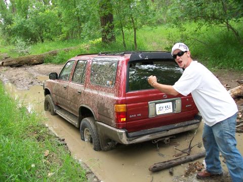 1988 Ford F-150 - Man poses next to a red Toyota 4Runner stuck in a muddy ditch.