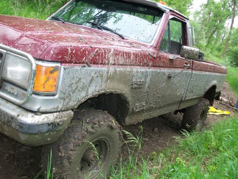 1988 Ford F-150 - This pickup truck is heavily covered in mud, suggesting it has been driven off-road.