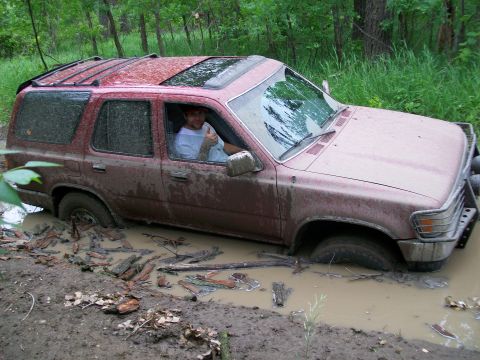 1988 Ford F-150 - A red SUV is stuck in a muddy ditch with a driver giving a thumbs up.