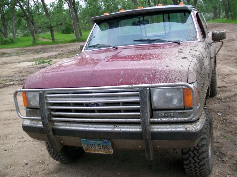 1988 Ford F-150 - Mud-covered 1988 Ford F-150 pickup truck with a brush guard and 4x4 badging.