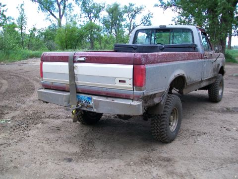 1988 Ford F-150 - This pickup truck features a two-tone paint scheme and off-road tires, with a strap securing the tailgate.