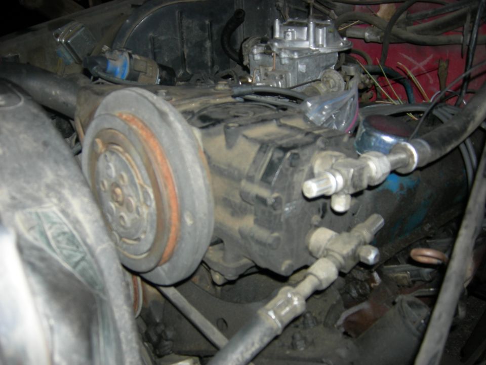 Dirty V8 engine bay showing carburetor and accessory pulley