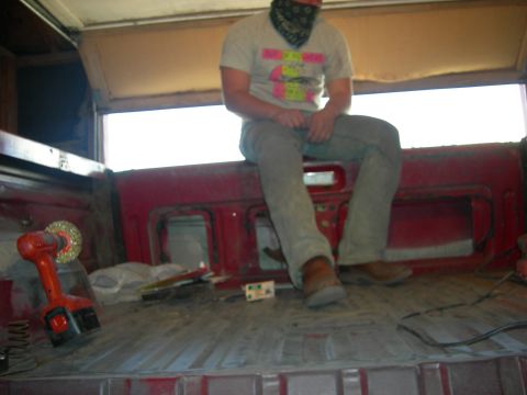 1979 Ford Bronco - Interior view of a red pickup truck bed with a person sitting on the edge.