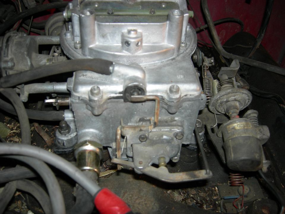 Close-up of a carburetor with linkages and hoses