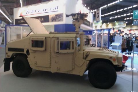 1991 Ford Crown Victoria - A tan AM General HMMWV, also known as a Humvee, is displayed with its hood open and a weapon system mounted on top.