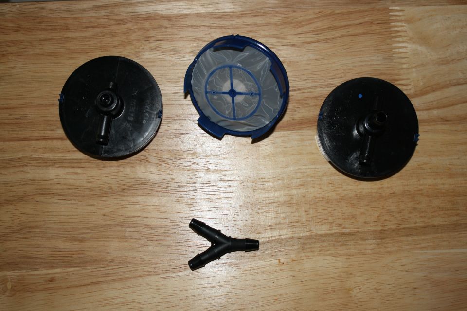 Fuel filter housing, filter element, and a Y-connector fitting laid out on a wooden surface