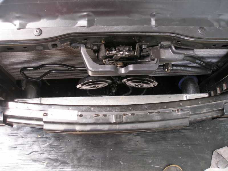 Front of a car with bumper removed showing radiator, hood latch, horns and aluminum crash bar