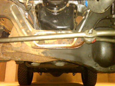 1995 Ford Bronco - The underside of a vehicle reveals its mechanical components and a portion of a tire.