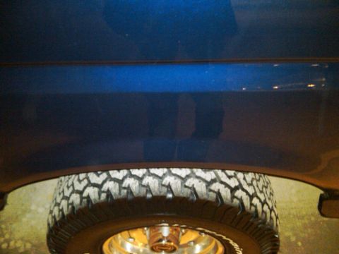 1995 Ford Bronco - A close-up view of a blue vehicle's side panel and tire, with a watermark from Supermotors.net visible.