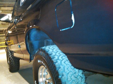 1995 Ford Bronco - Close-up view of the rear quarter panel and tire of a dark blue SUV. The registry claims it is a 1995 Ford Bronco, but this is not confirme…