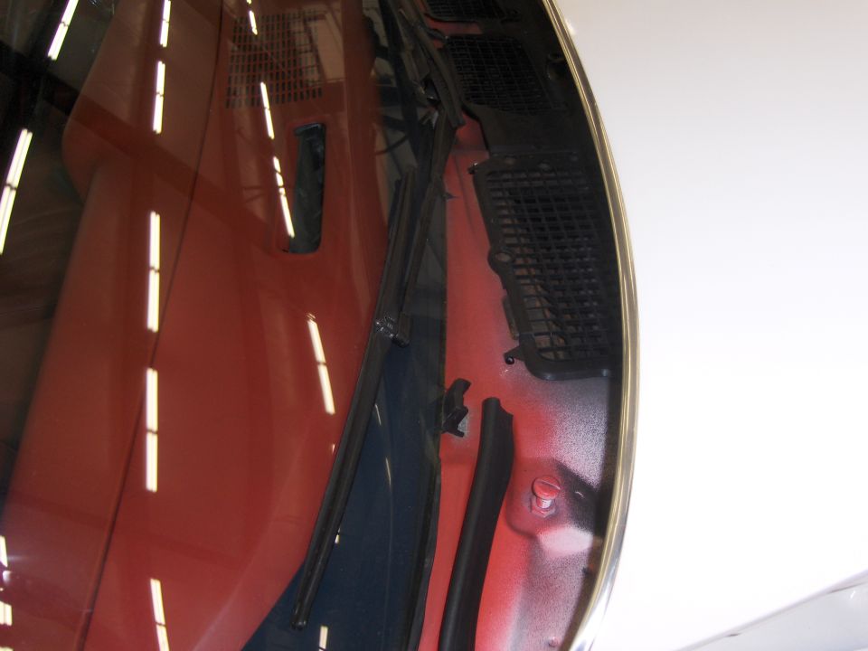 Close-up of a red car's hood and windshield wiper area