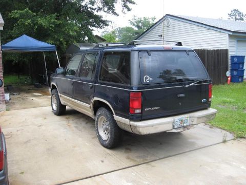 1991 Ford Explorer - The rear of a dark blue Ford Explorer is visible, parked in a residential driveway.