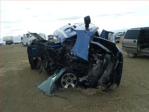 2005 Dodge 3500 - A severely damaged blue 2005 Dodge 3500 truck sits in a lot, likely after a significant accident.