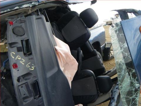 2005 Dodge 3500 - The interior of a severely damaged truck shows a deployed airbag and a torn door panel with handwritten markings.