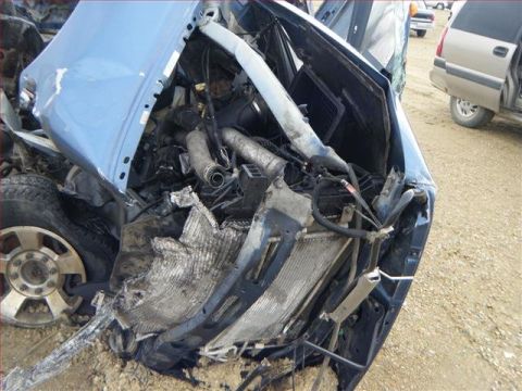 2005 Dodge 3500 - The front end of a heavily damaged blue truck shows its engine compartment, radiator, and other internal components.