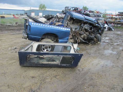 2005 Dodge 3500 - This 2005 Dodge 3500 pickup truck is heavily damaged and sits in a junkyard with other vehicles.