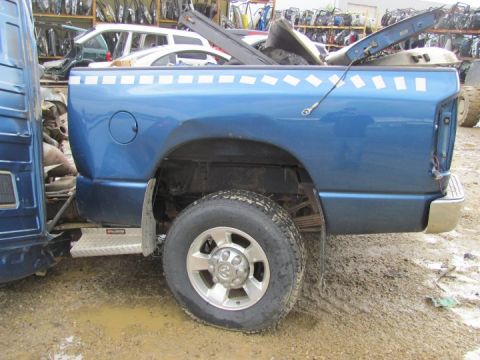 2005 Dodge 3500 - The rear section of a blue pickup truck is visible, showing the wheel well and part of the bed.
