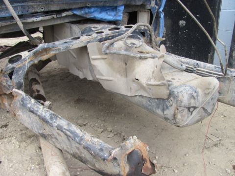 2005 Dodge 3500 - The vehicle's undercarriage is heavily damaged, with rust visible on the frame and a dented fuel tank.