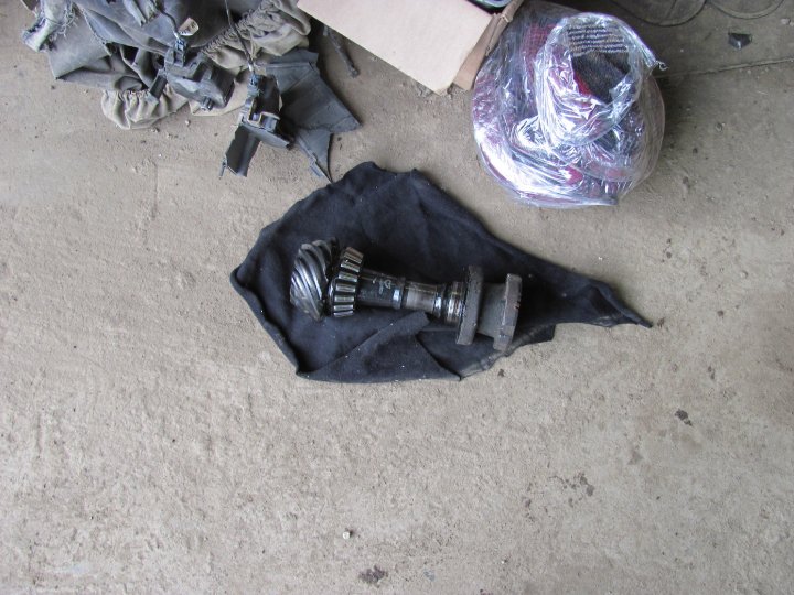 Differential gear and shaft assembly on black cloth, with other parts and a box in the background