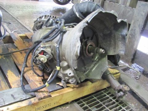 2005 Dodge 3500 - A damaged transmission, likely from a heavy-duty vehicle, sits on wooden pallets with its casing severely compromised.