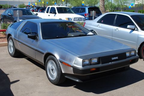 2005 Subaru Impreza - A DeLorean DMC-12 is parked in a lot with other vehicles, including a white pickup truck and a silver sedan.