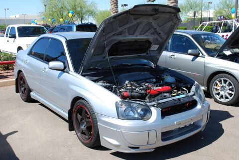 2005 Subaru Impreza - A silver Subaru Impreza WRX sedan is parked with its hood open, revealing the engine and red accents.