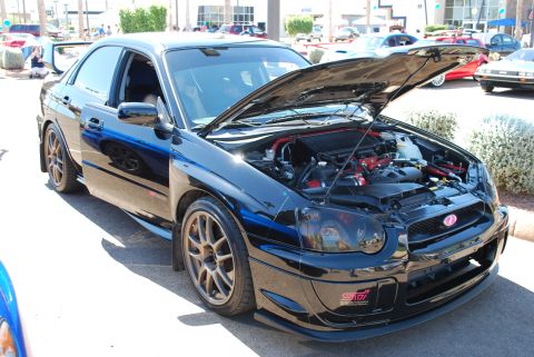 2005 Subaru Impreza - Black 2005 Subaru Impreza WRX STI sedan with hood open, parked outdoors at a car show.