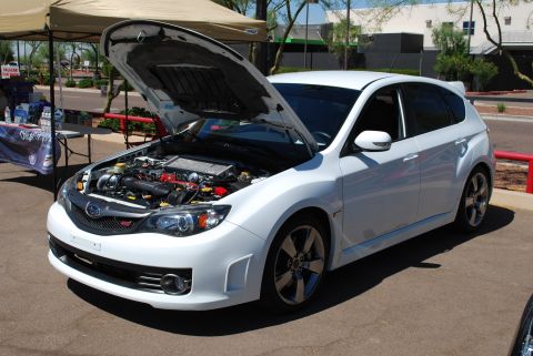 2005 Subaru Impreza - White Subaru Impreza WRX STI hatchback at an auto show, hood open to display the engine.