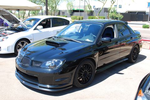 2005 Subaru Impreza - A black Subaru Impreza WRX STI is parked at an outdoor event, with a white car visible behind it.